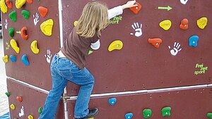 Ein Kind klettert an einer Boulderwand
